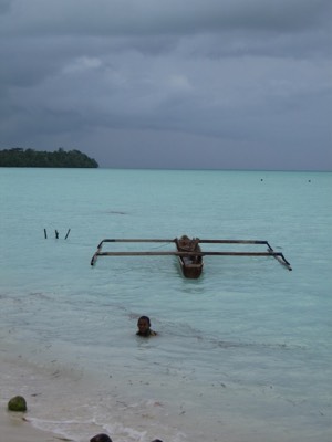 Kid with outrigger canoe at high tide